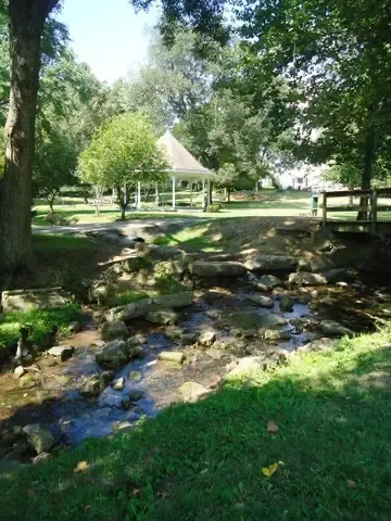 A Creek with trees and a gazebo in the background